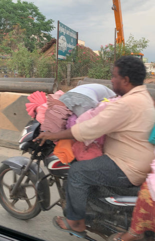 Piles on fabric being held by a man on a motorbike