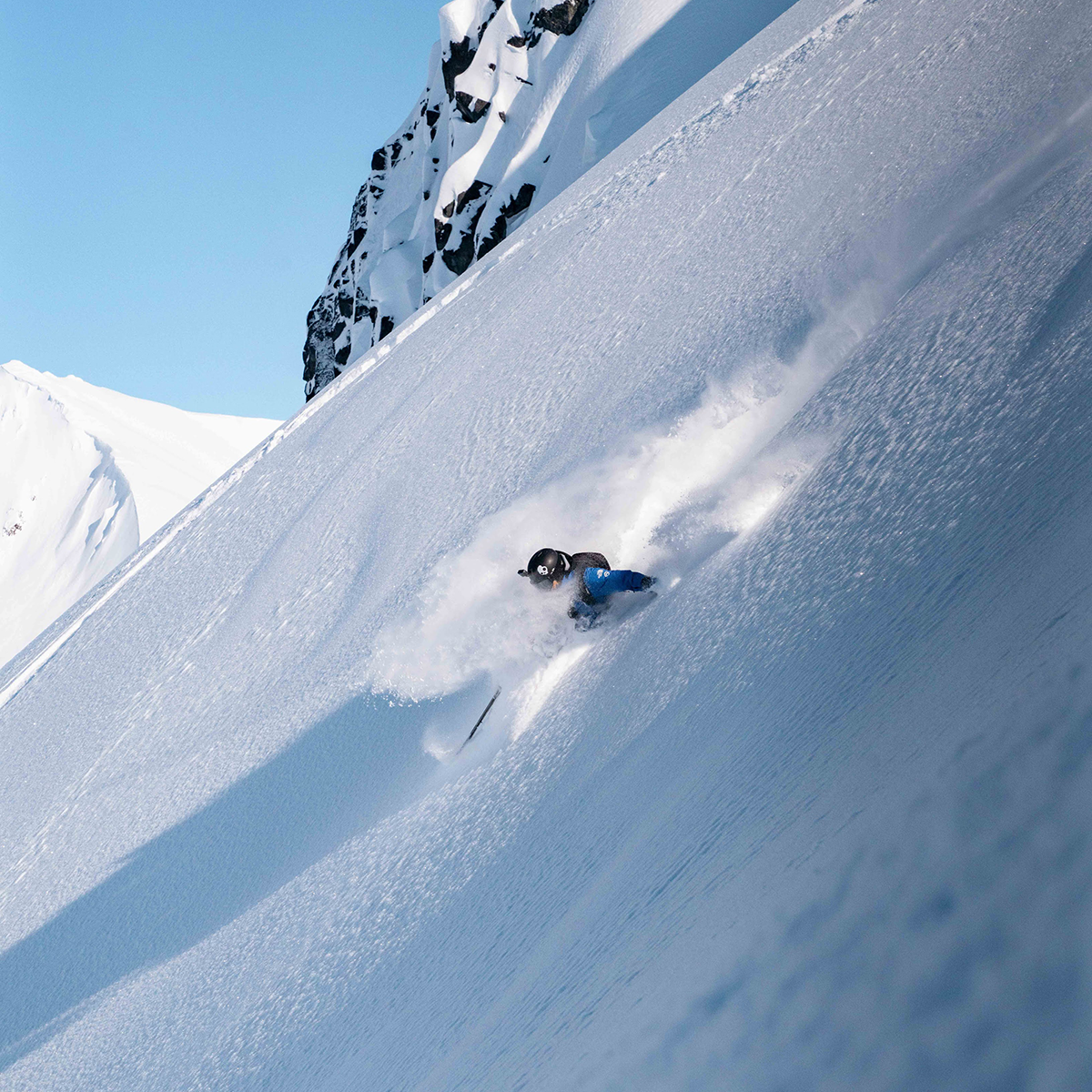 freeride skier performs slash turn in deep powder