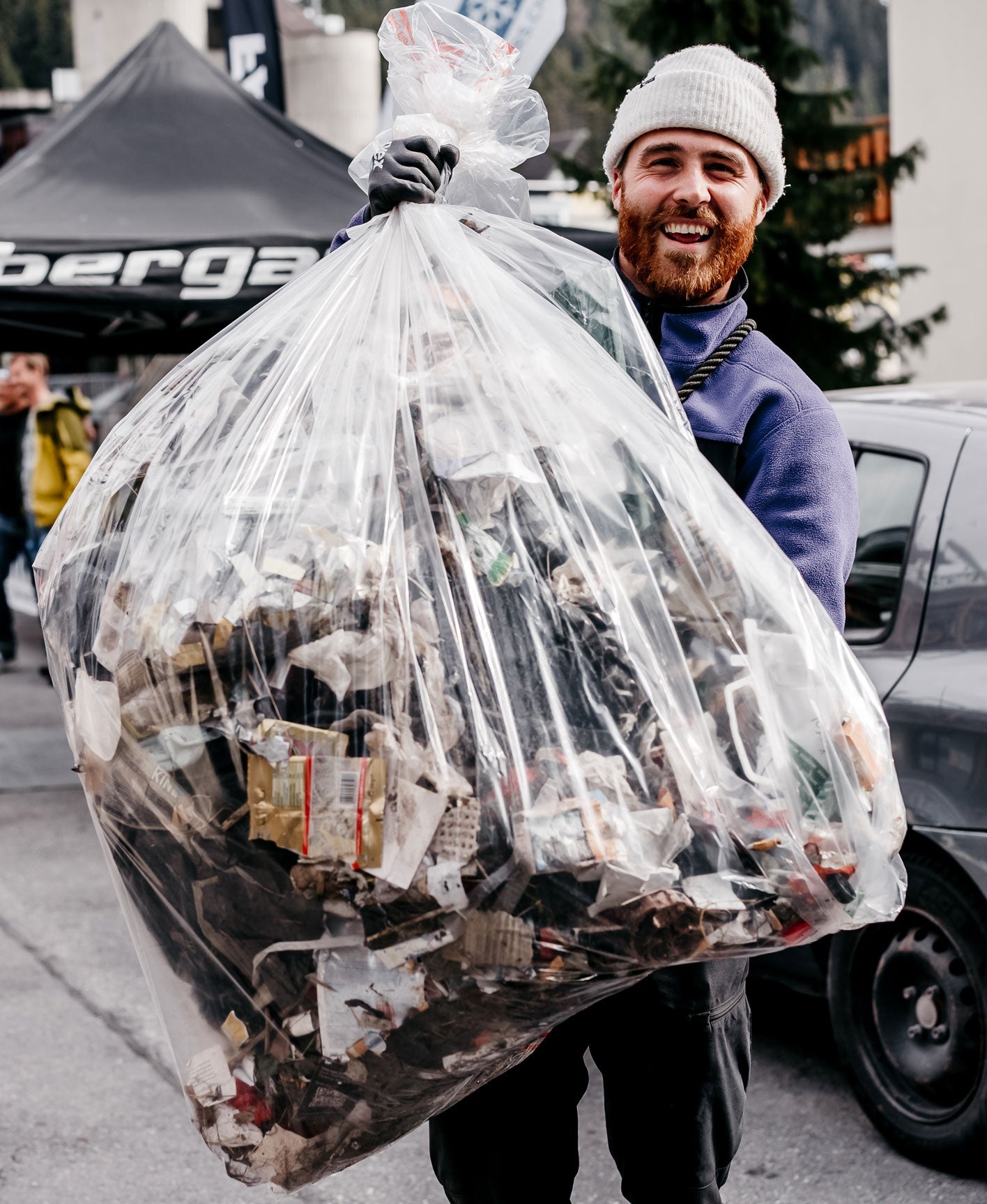 bearded man with white hat smiling holding big rubbish bag