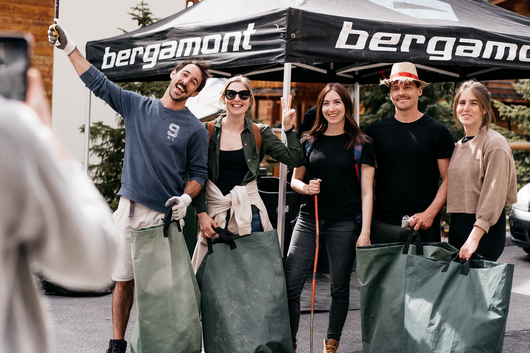 three women and two men smilling holding rubbish bags