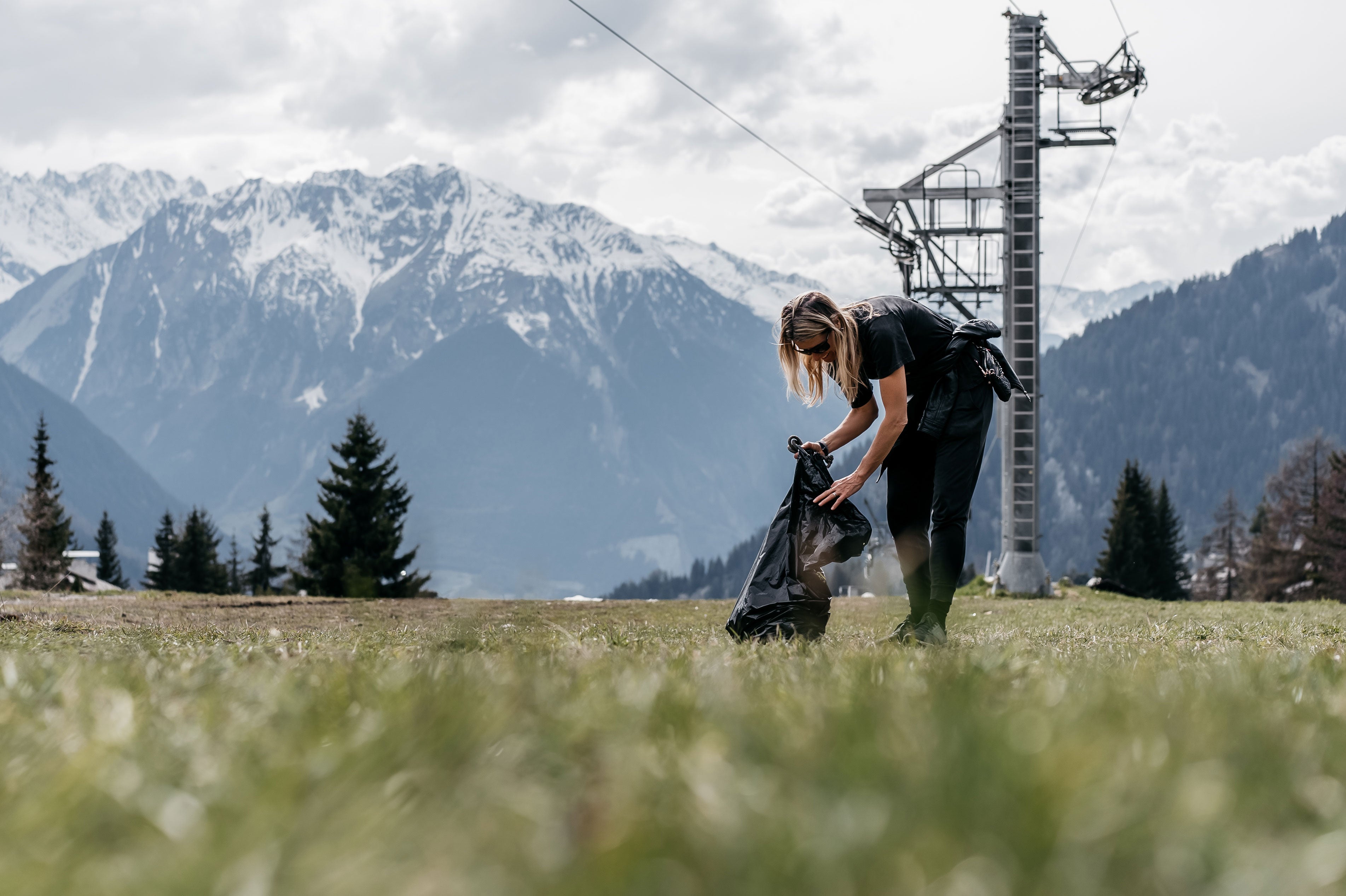 Frauen sammeln Müll auf einem Feld mit Bergen im Hintergrund