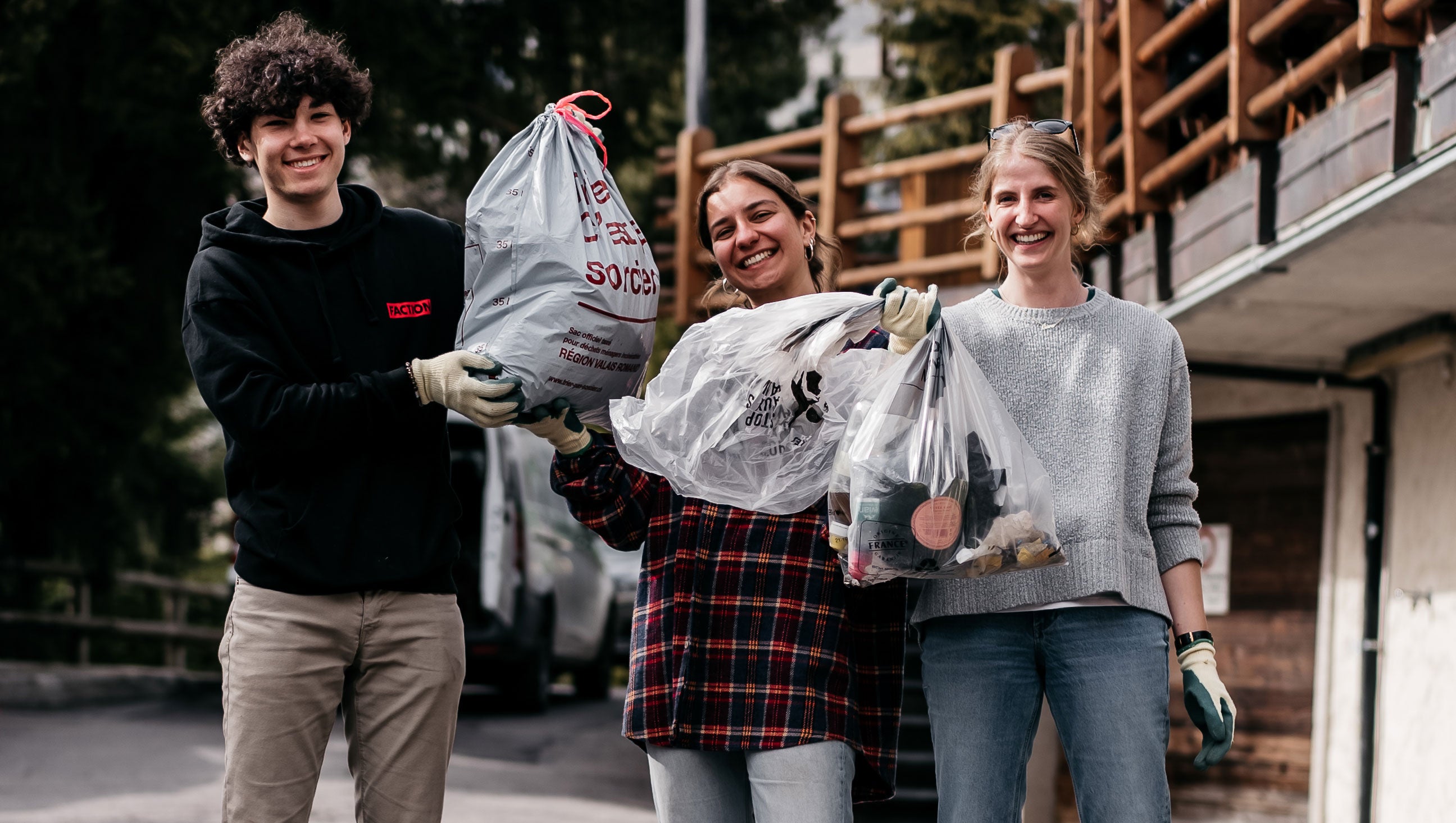 two women and one man smiling holding rubbish bags at chest height