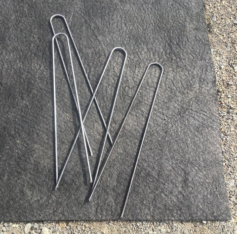 12-inch 8-gauge Heavy Duty Landscape Staples laying on the ground on a piece of cloth