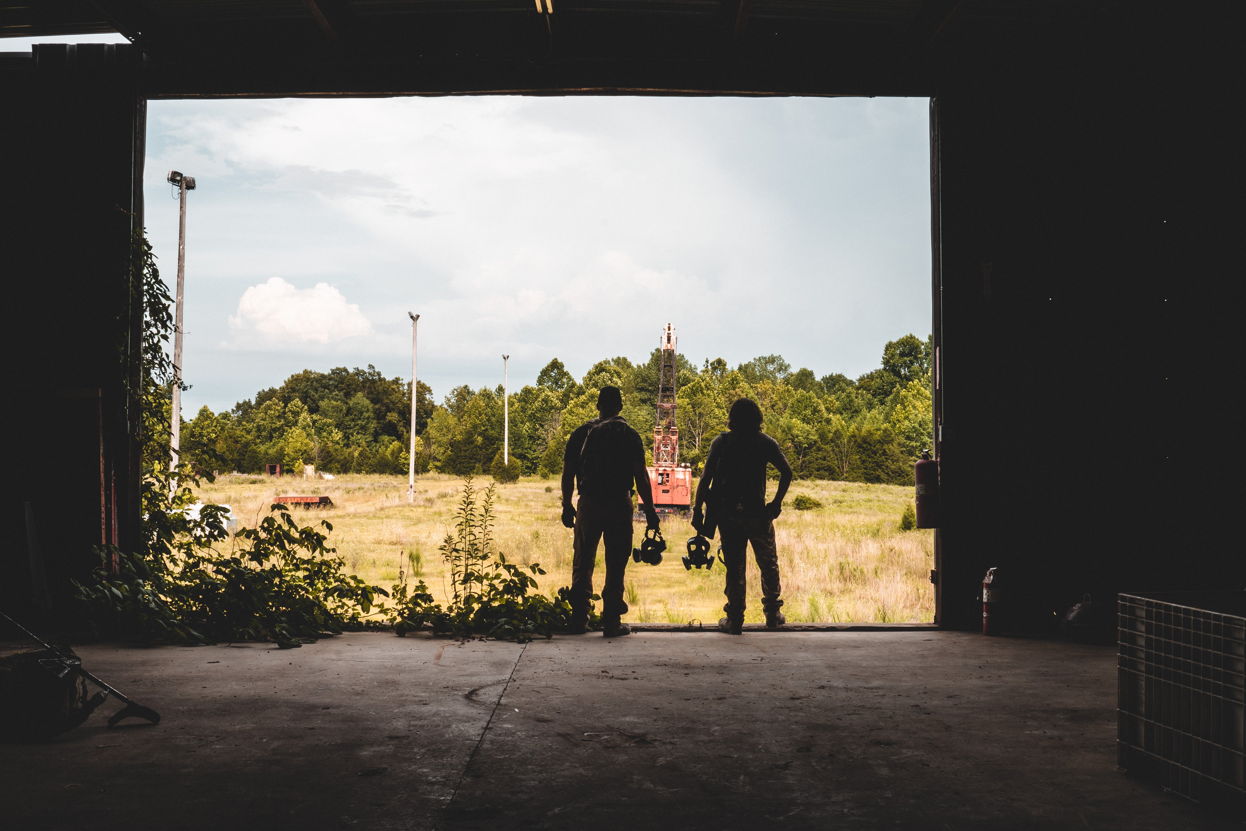 2 men standing, holding a gas mask.