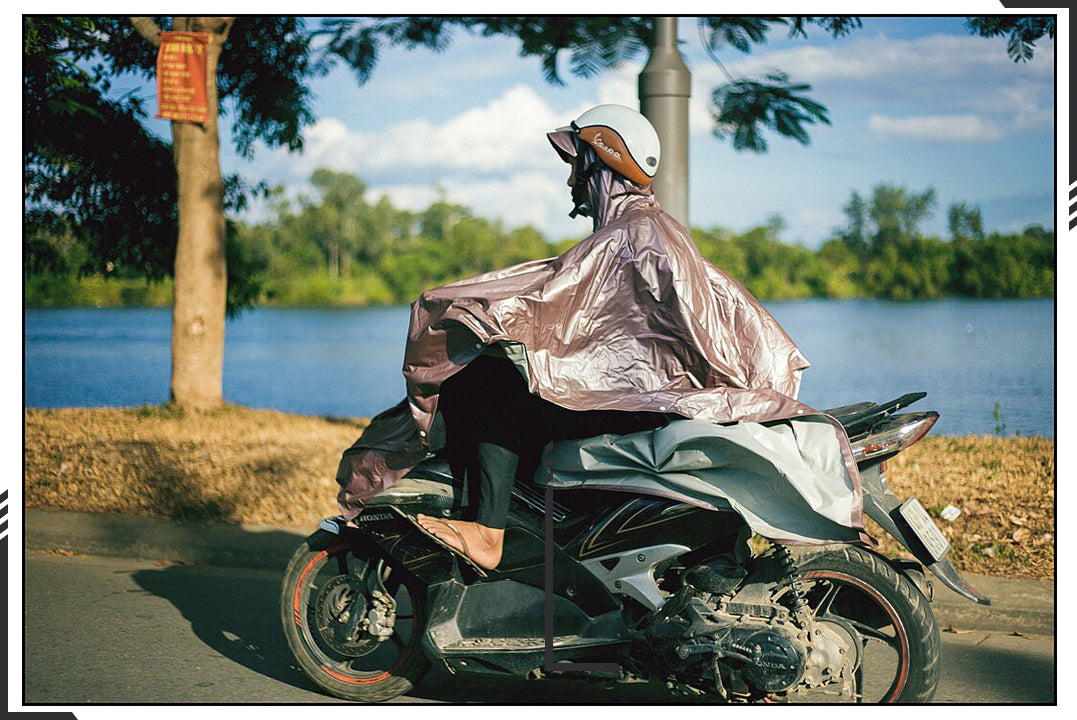 A man riding a vehicle wearing a poncho