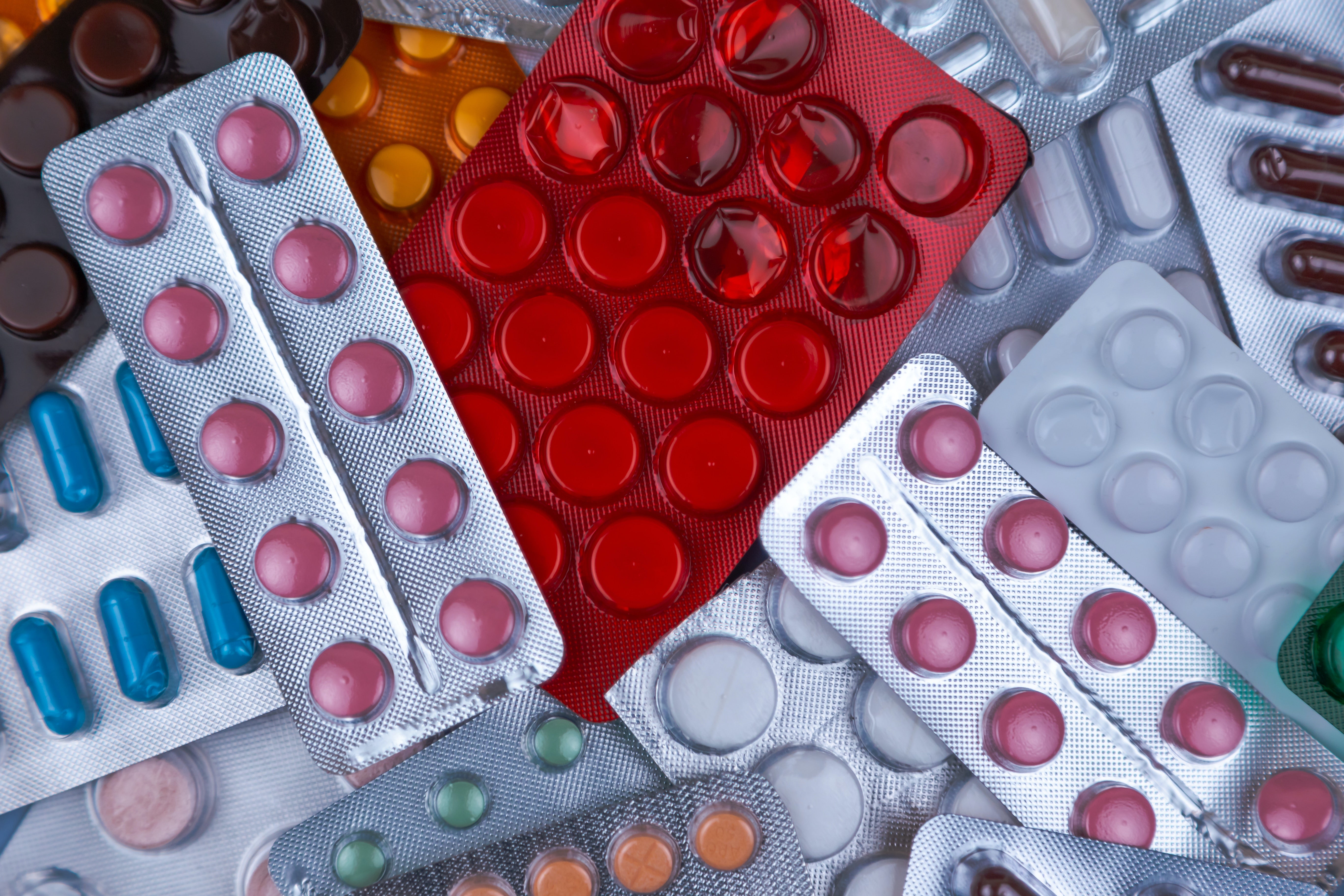 Pile of blister packs of colorful medicine tablets.