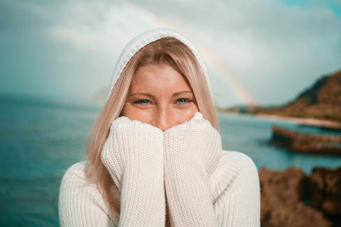 Cheerful woman with a sea-and-rainbow backdrop