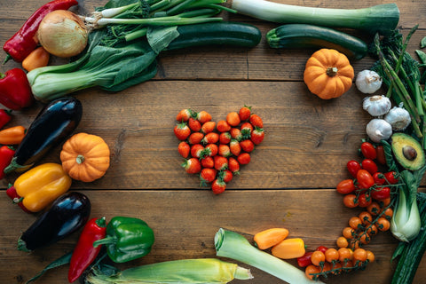 Red, yellow, green, and purple fruits and vegetables on a wooden table