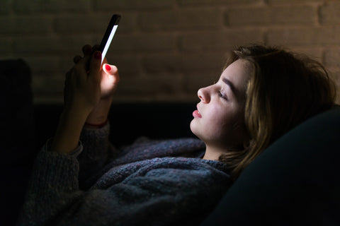 Woman using a mobile phone while lying in bed