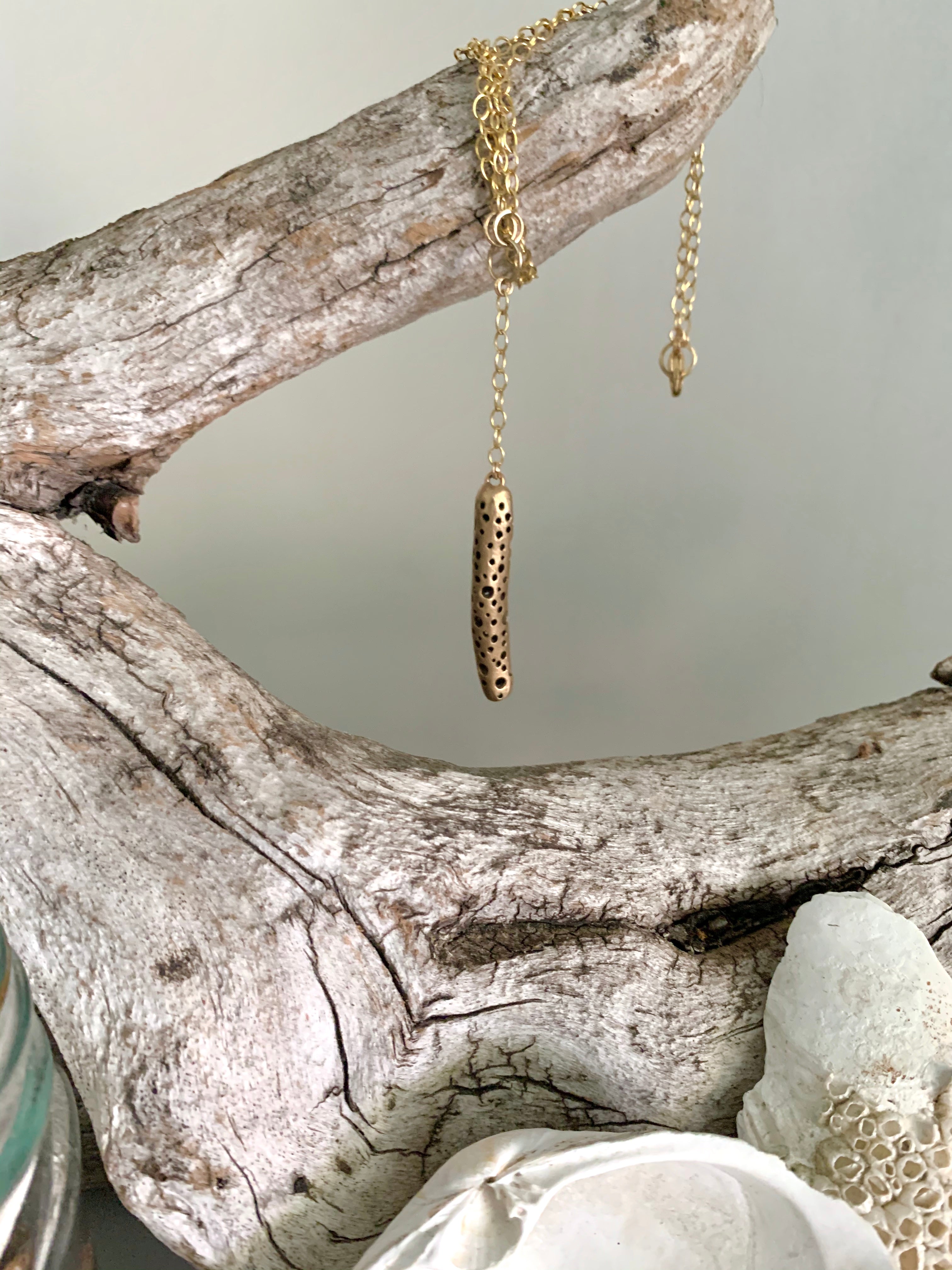 Bronze drop necklace hanging from driftwood