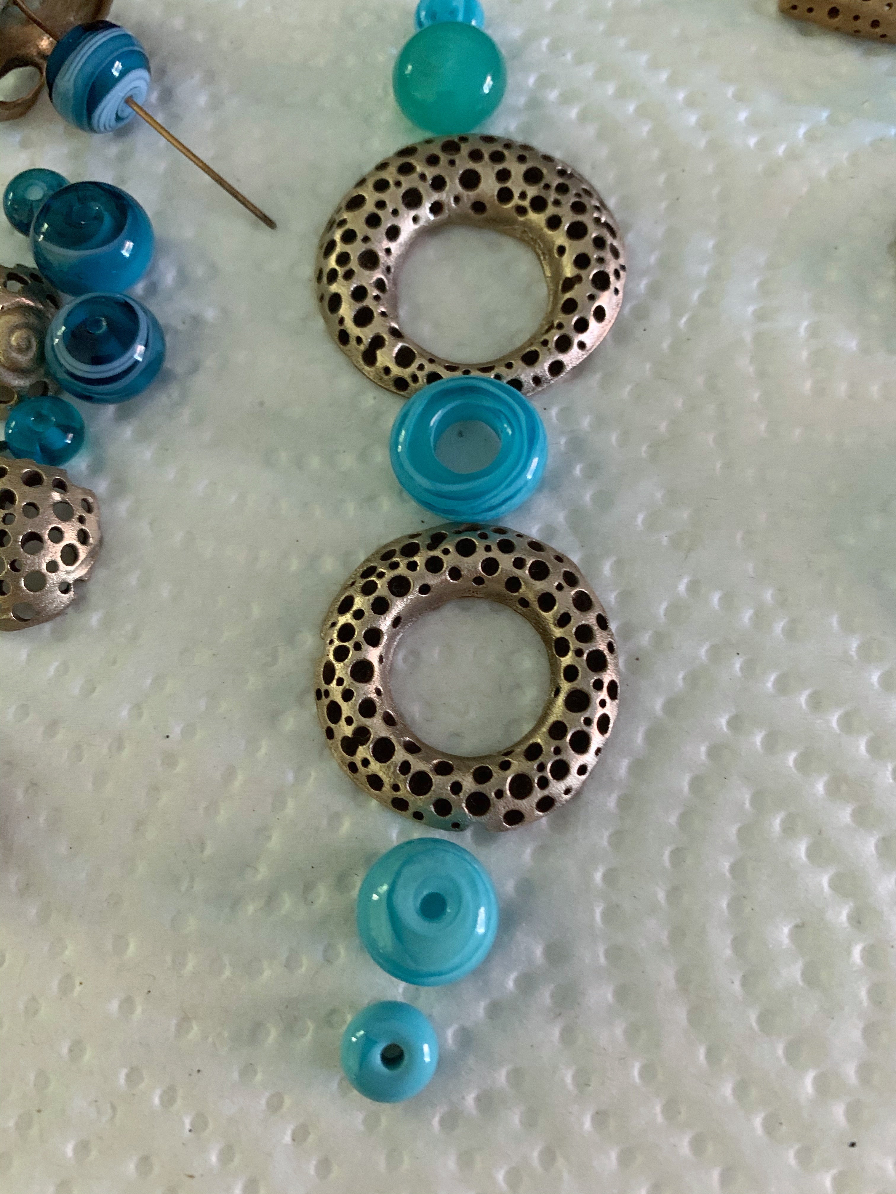Sea blue glass beads and bronze rings in statement necklace work in progress