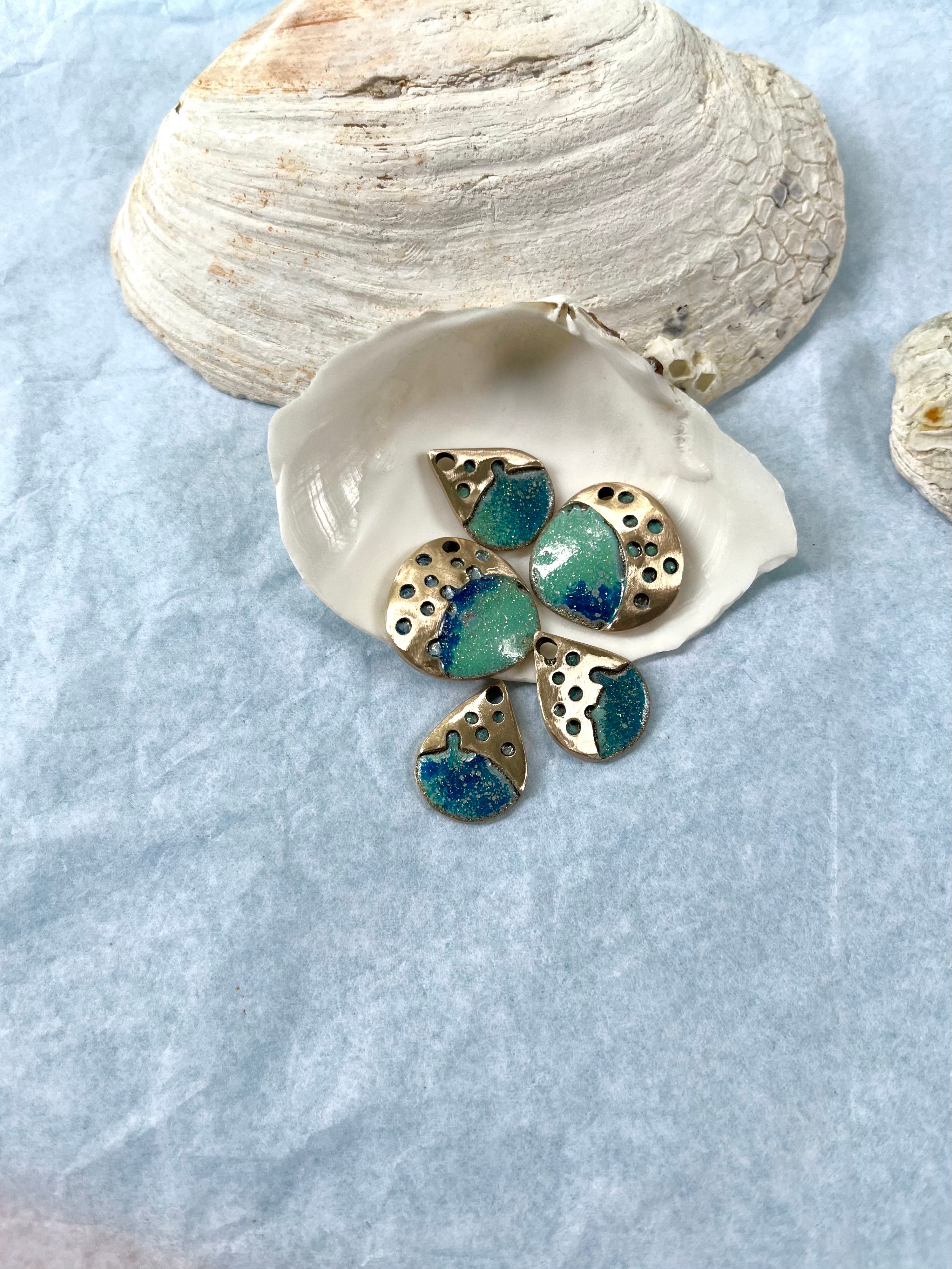 Ocean inspired bronze jewelry pieces tumbling from a seashell
