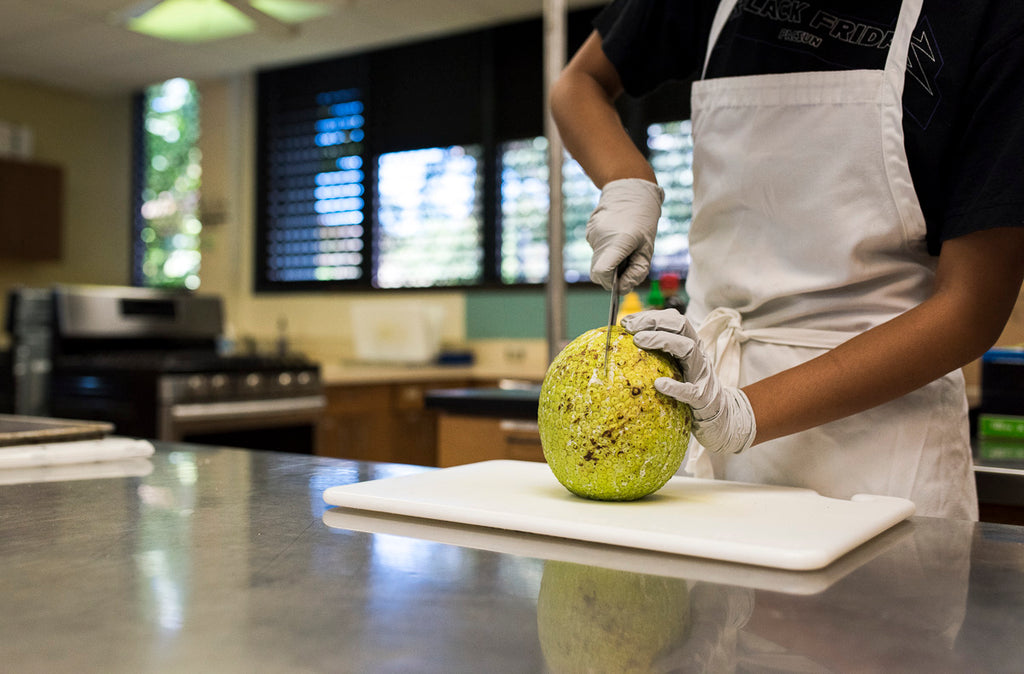 student cutting into ulu fruit