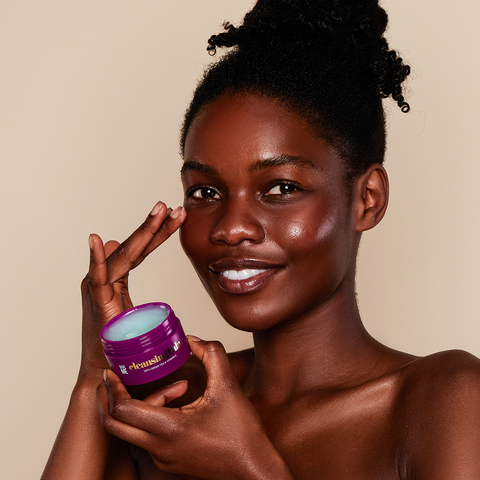 A woman holding the Give Me Cosmetics Green Tea & Vitamin E Cleansing Balm.