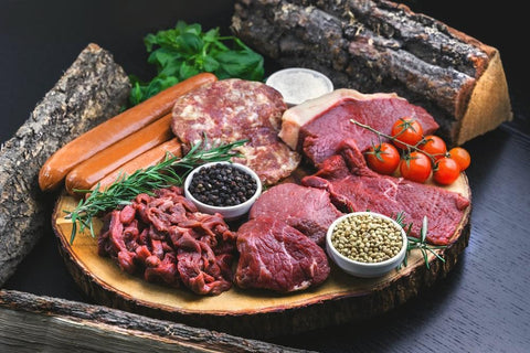 Various meats and spices sit on a log plate together