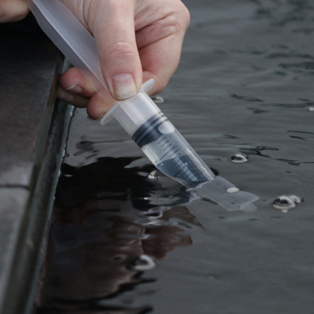 Using a syringe to collect a sample of pond water
