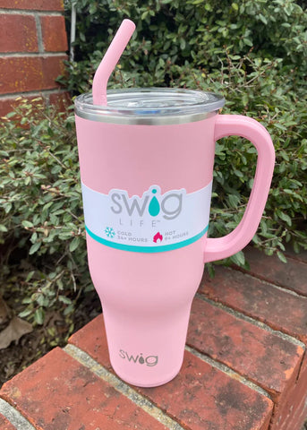 Light Pink Swig 40oz Mega Mug sitting on a brick flower ledge with a green plant in the background.