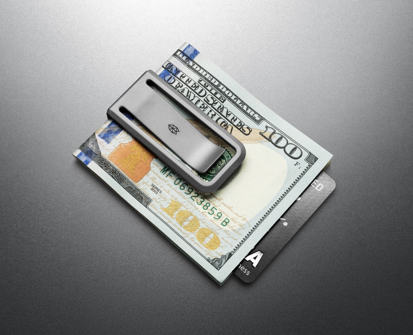 The Martindale titanium money clip with cash and cards on a countertop.
