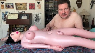 White male with sex doll on bed