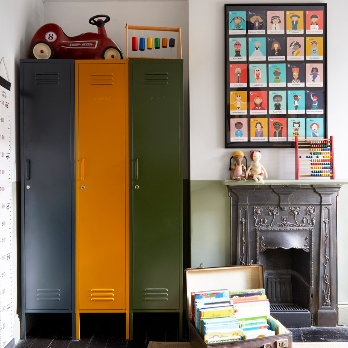 In a retro-inspired room, three Skinnys in Slate, Mustard and Olive sit flush into a nook next to an ornate Victorian fireplace. There is a vintage red metal toy car on top, and an open case full of colorful books on the floor.