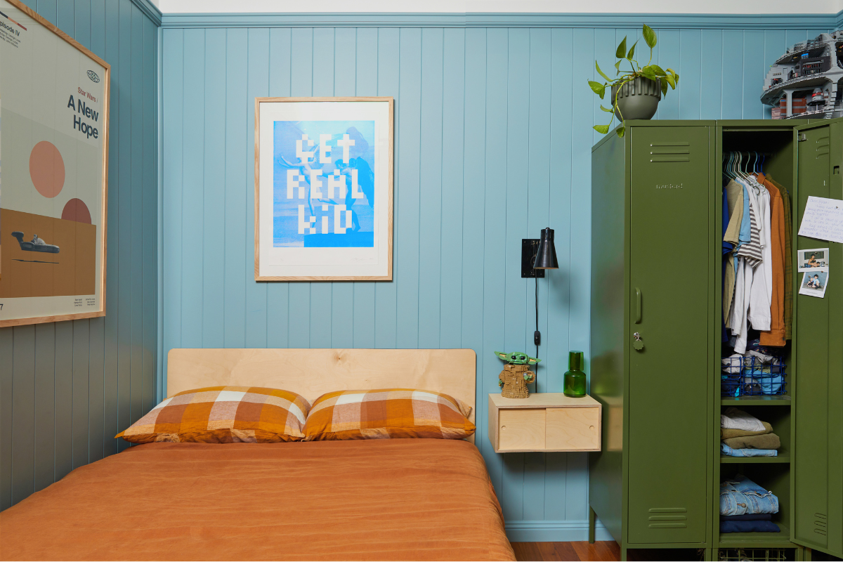 A small Yoda figurine sits next to Dylan's bed and there is a poster reading 'get real kid' on the wall. An Olive Twinny has one door open to reveal Dylan's clothes hung inside.