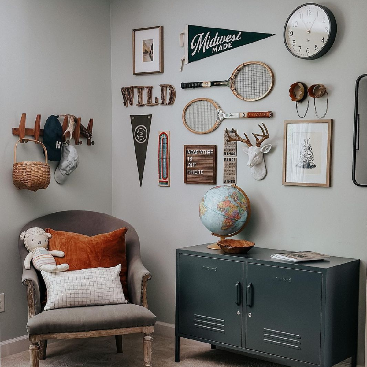 A Slate Lowdown sits in a corner next to a grey velvet armchair. Behind it there is a gallery wall displaying vintage style sports items such as wooden rackets and team flags.