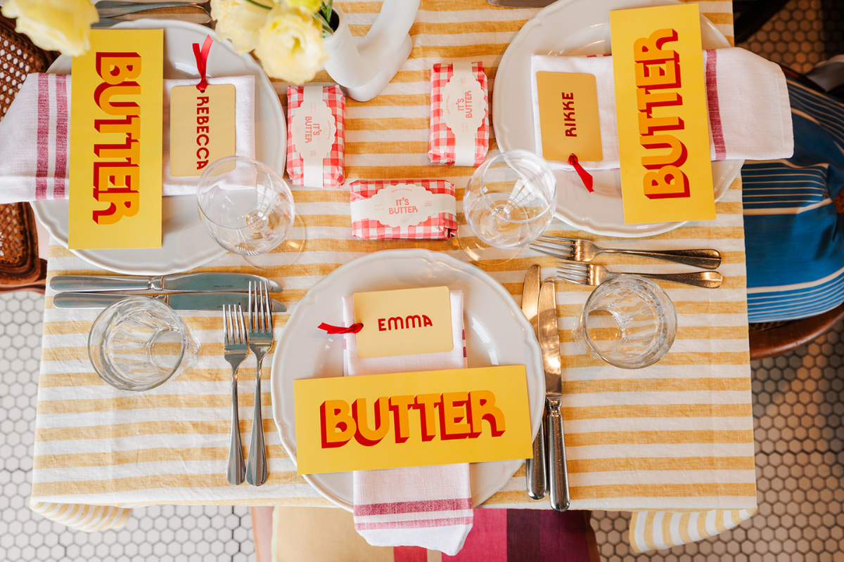 The Butter tablescape featuring Butter coloured menus with red lettering, place cards, and salted butter candles.