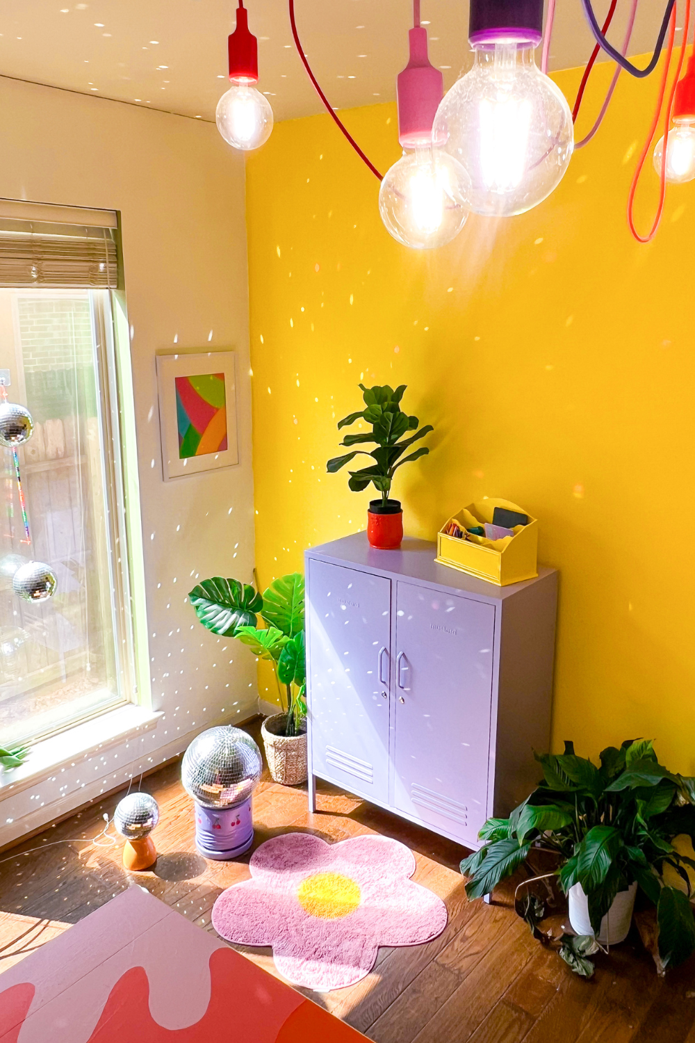 A Lilac Midi sits against a yellow wall, with light flecks reflecting off a disco ball. The room is filled with plants and brightly coloured decor pieces.