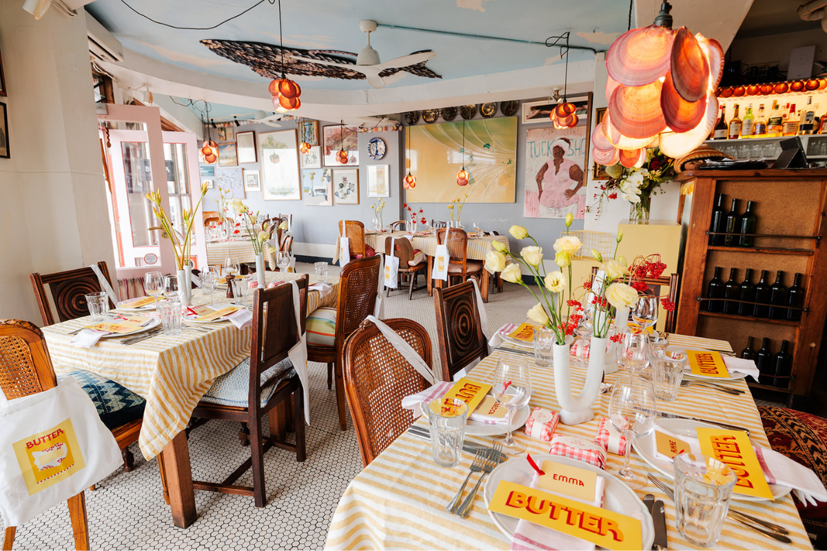 The interior of Sean's Bondi, styled for the Mustard Made Butter launch. There are Butter-coloured striped tablecloths, butter place cards and flowers in shades of yellow.