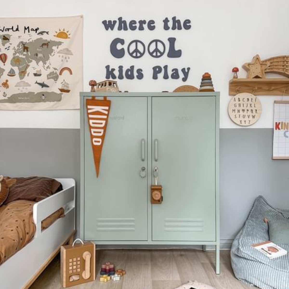 A Sage Midi sits in a child's room underneath lettering that reads 'where the cool kids play.' There is a fabric world map on the wall and soft furnishings in neutral earthy shades.