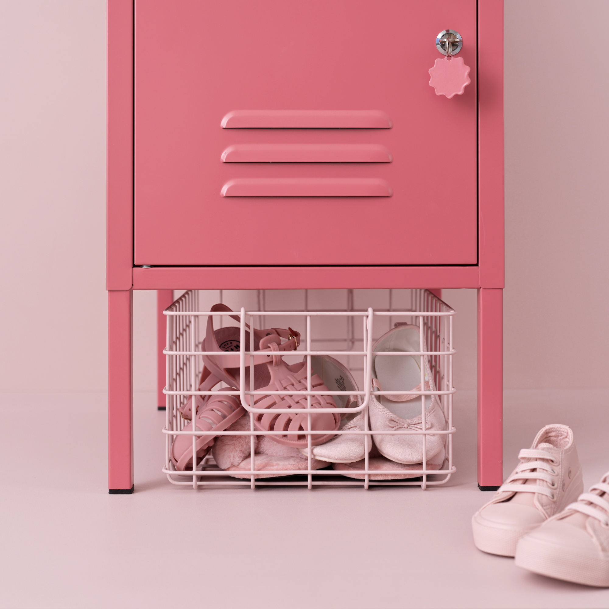 A large, blush pink coloured basket filled with kids shoes underneath The Shorty Locker in Berry.