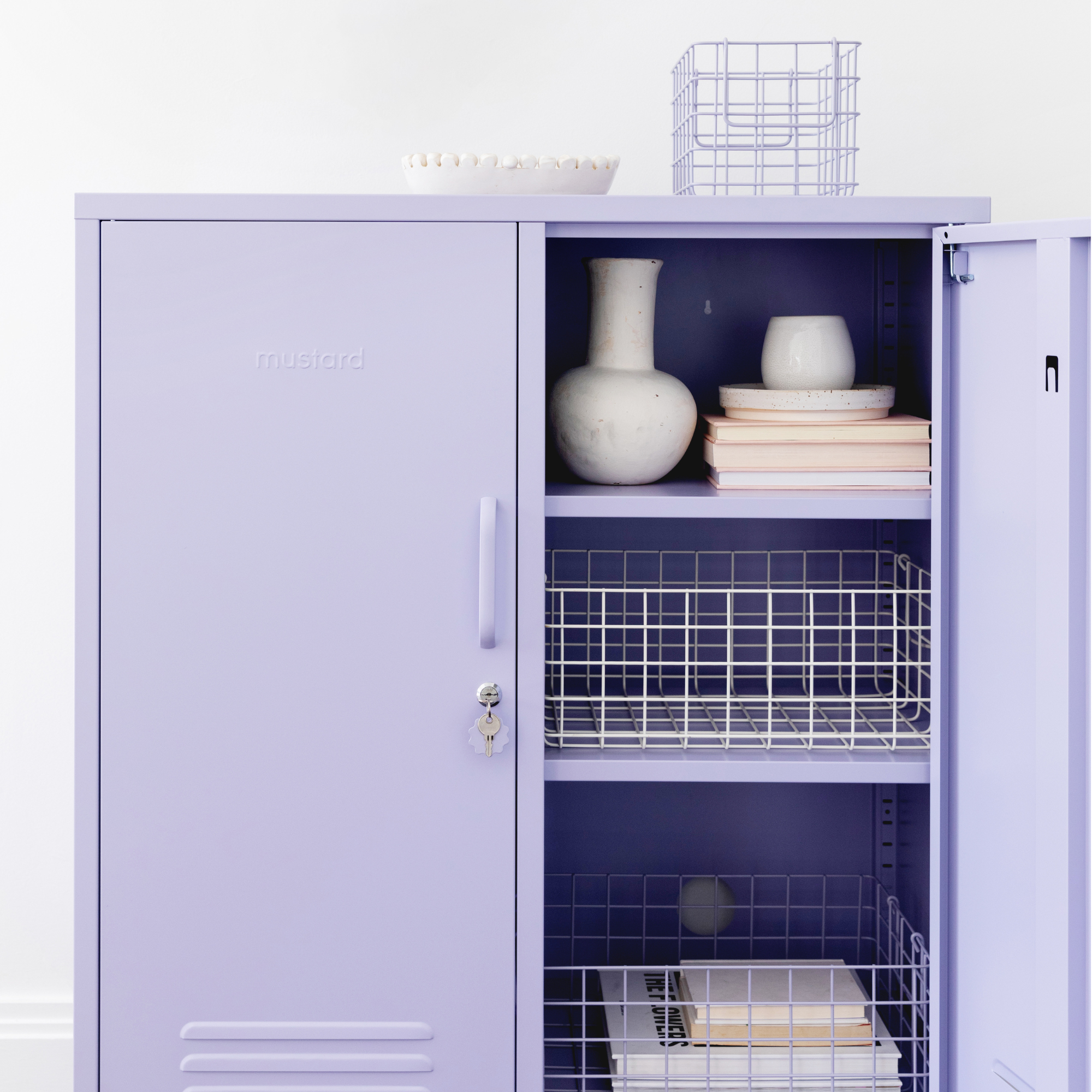 A Lilac Midi sits with one door open and one door closed. Inside, The Baskets are styled with pastel coloured books and stoneware vases.