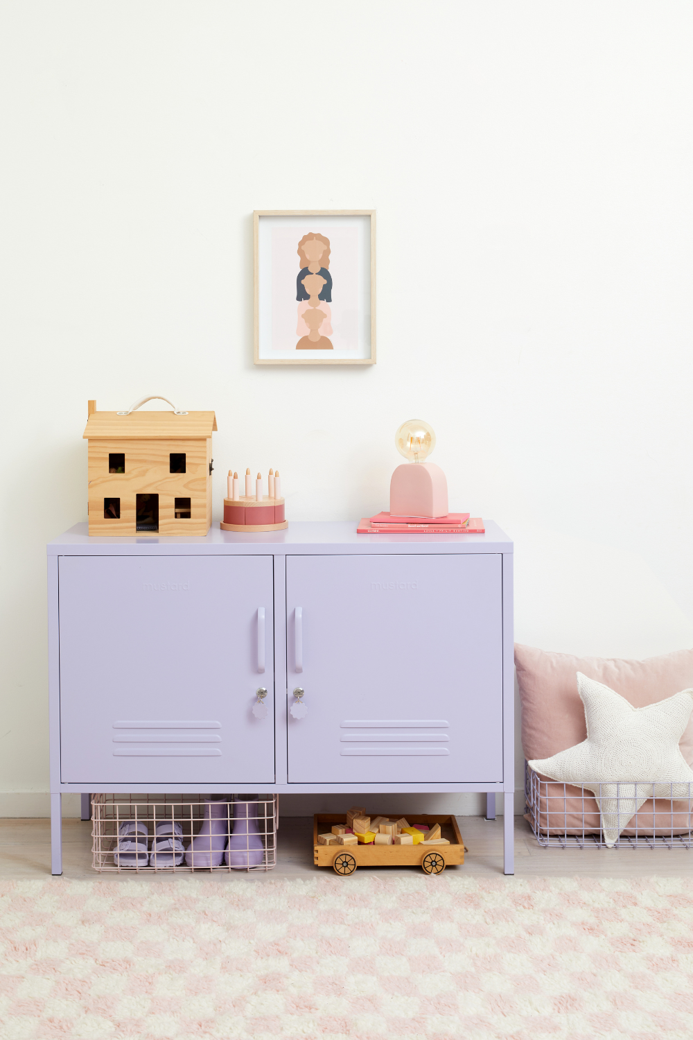A Lilac Lowdown sits in a kids room styled with wooden toys and Blush soft furnishings. There is a blush and white checked rug on the floor.