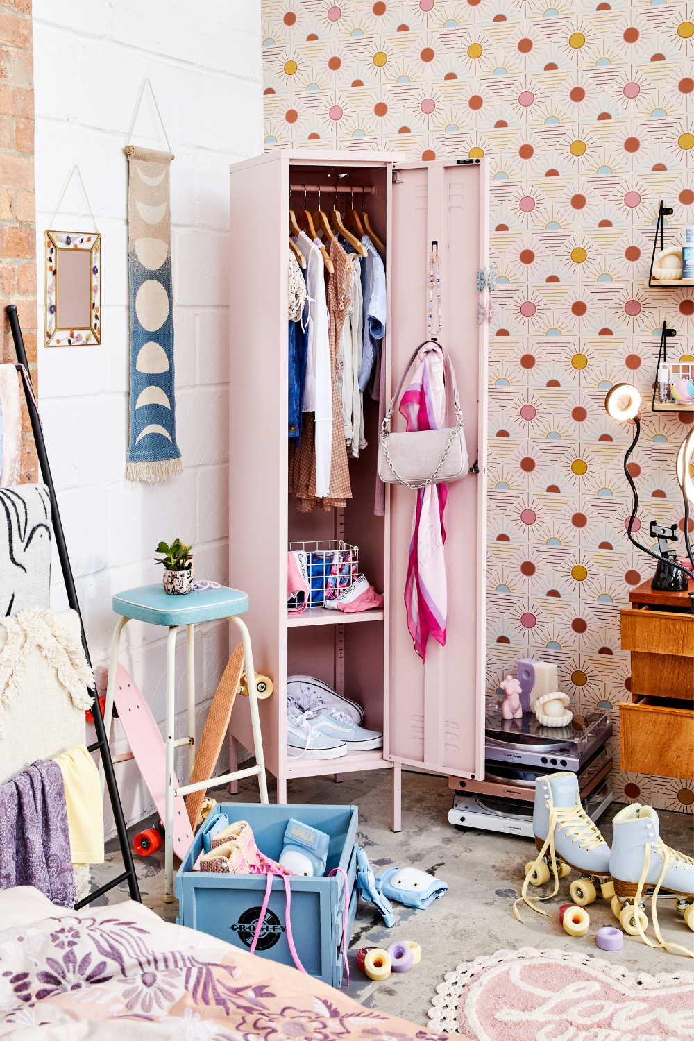 A Blush Skinny is open to reveal clothes, bags and accessories, while on the floor lie skateboards, rollerskates and records in pastel colours.