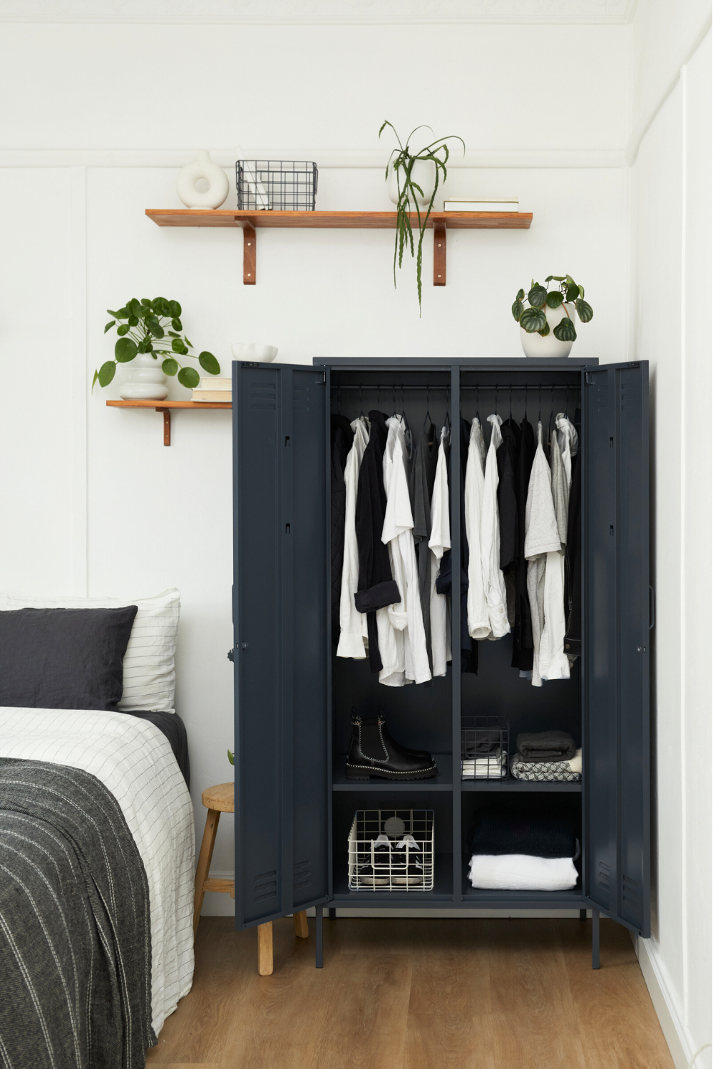 A Slate Twinny is styled in a bedroom. Its doors are both open, showing a monochromatic wardrobe inside including hanging clothes, and shoes.