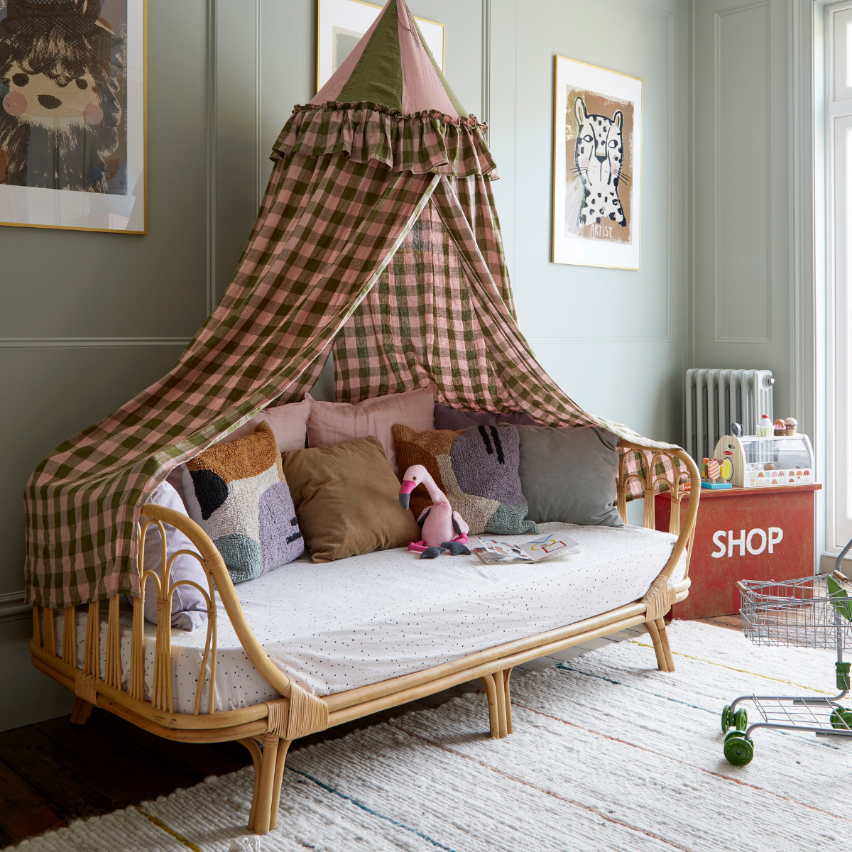 A day bed with a pink and green canopy hanging above.