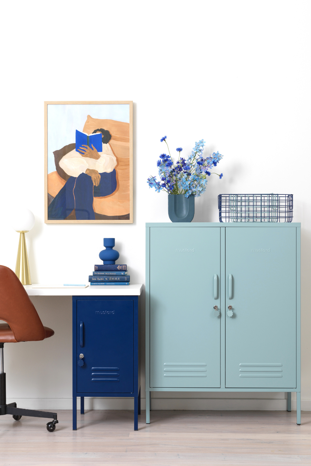 In a home office setup, an Ocean Midi is styled next to a desk with a Navy Shorty underneath it. There is a tonal artwork on the wall and a vase of blue flowers on top of the locker.