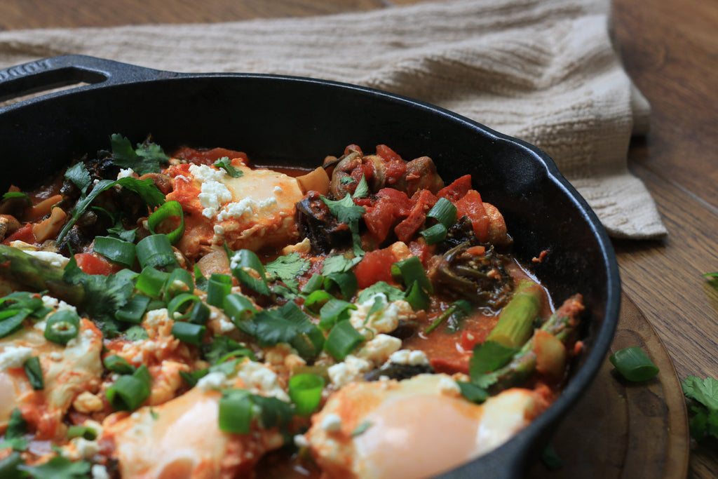 Cast iron skillet with fried eggs, chorizo, asparagus, green onion and more