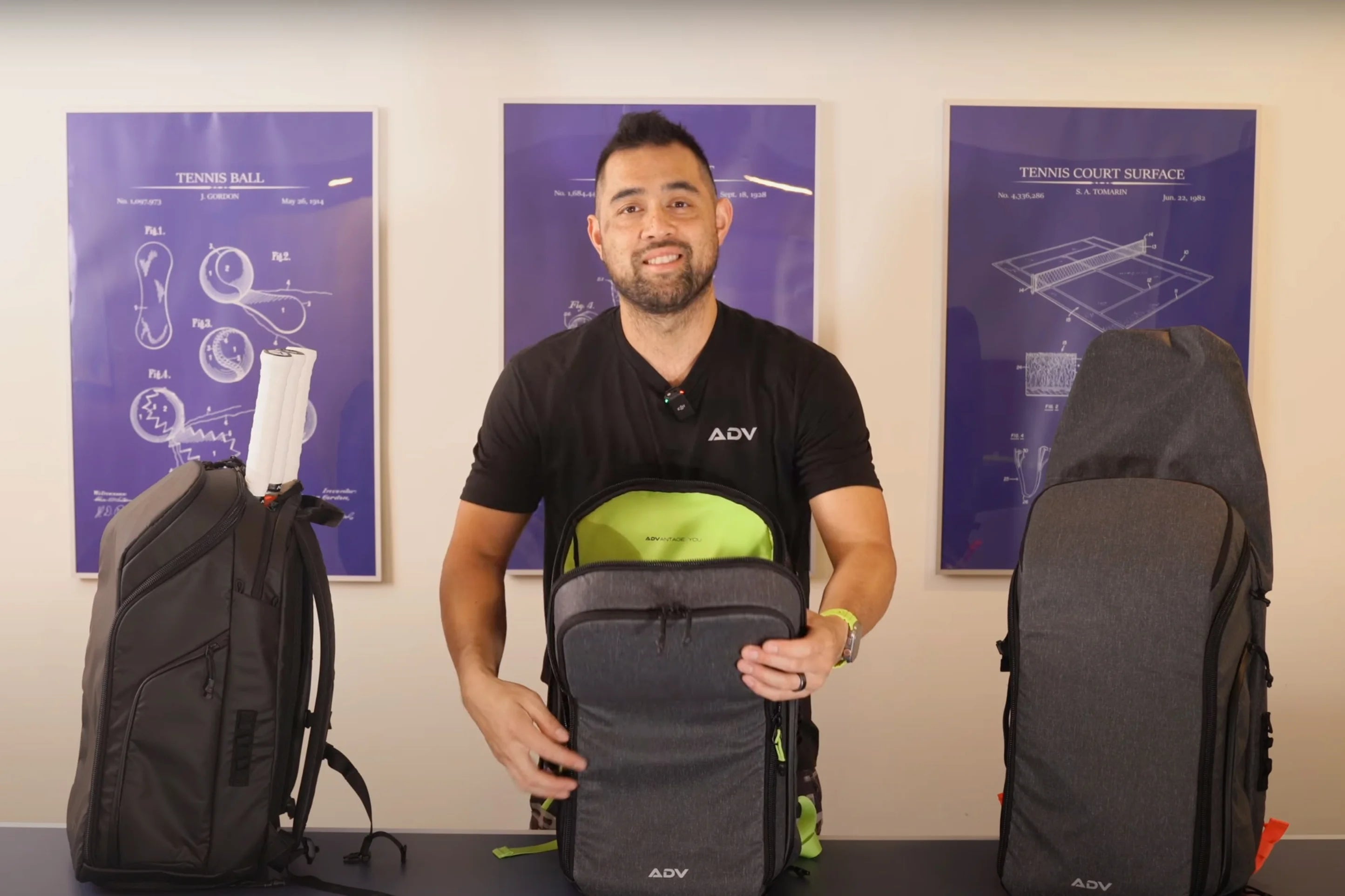 Man demonstrating ADV backpacks in front of tennis-themed posters.