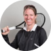 Person smiling and holding a tennis racket over their shoulder.