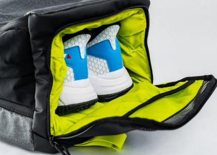 A pair of sneakers inside a black and neon green shoe bag.