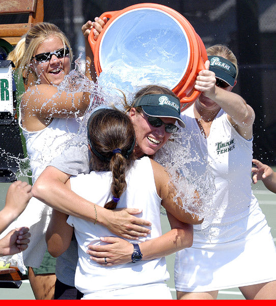 Meike Babel being washed by a barrel of water hold by two women while she is hugging a girl.