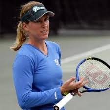 Meike Babel in a blue long sleeve shirt holding a racquet.