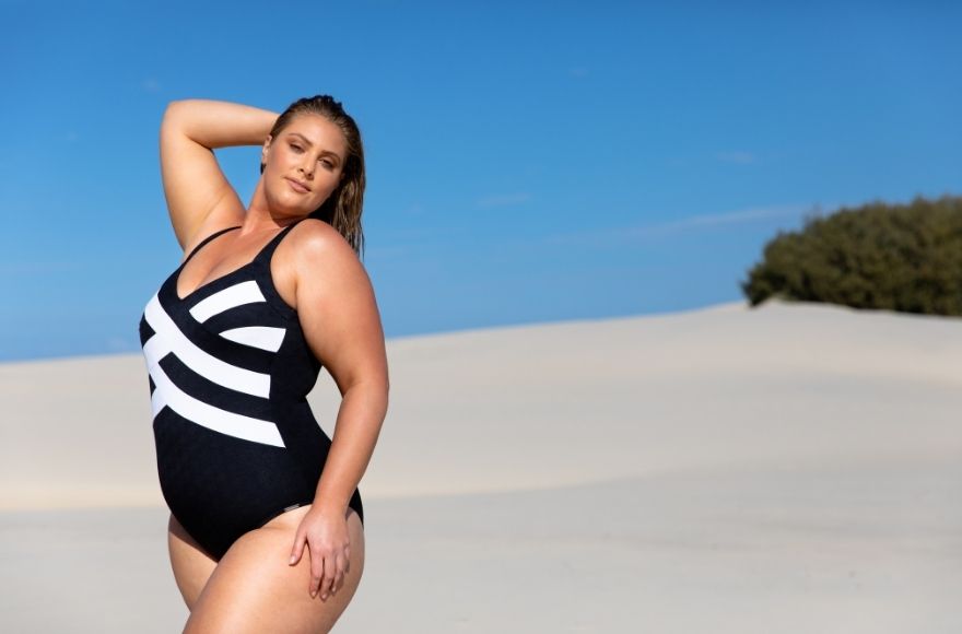 Blonde model poses on the sand dunes wearing Acapulco black and white criss cross one piece swimsuit