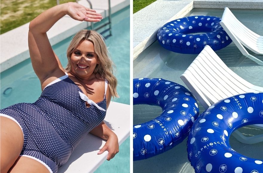 Woman reclines on diving board wearing navy and white polka dot one piece retro swimsuit