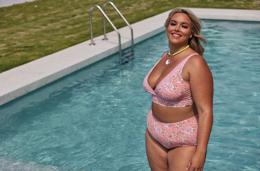 Woman poses in the pool wearing pink floral bikini