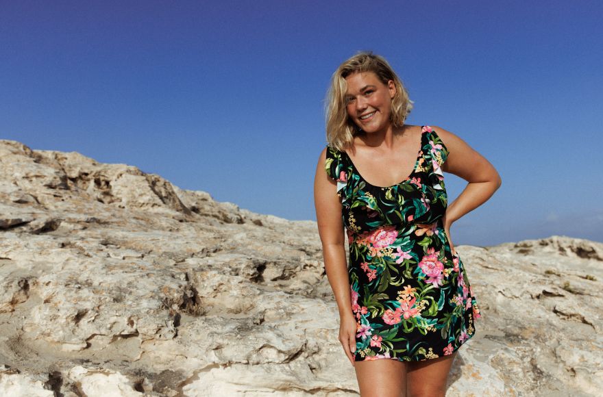 Woman with short blonde hair wears black floral frill swim dress