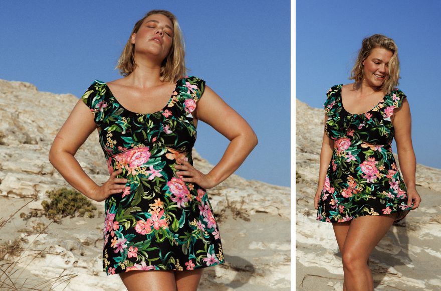 Woman with short blonde hair wears black, green, and pink floral swim dress. 