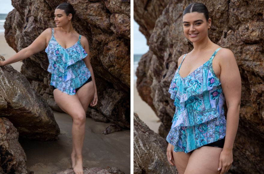 Woman with slicked back brown hair wears blue patchwork print ruffled tankini top with plain black pants