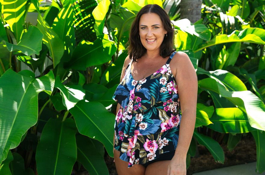 Woman with brown hair wears bright floral ruffle tankini top 
